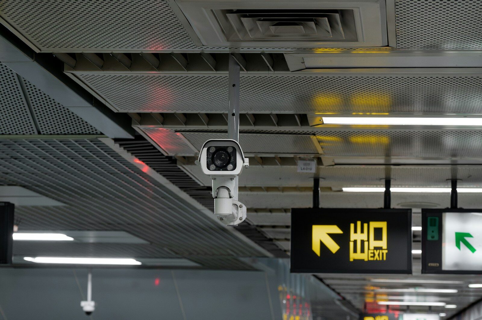 Security camera mounted on a ceiling with exit sign